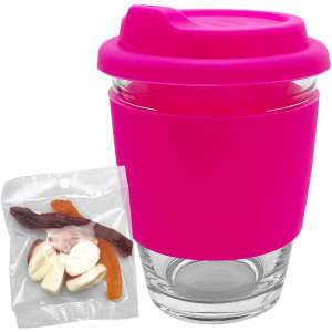 A reusable coffee cup with a bright pink silicone lid and grip, accompanied by a bag of assorted jelly candies.