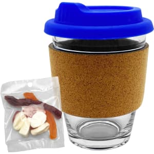 A glass coffee cup with a cork band and blue lid, accompanied by a bag of mixed lollies in various colours.
