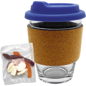A glass coffee cup with a cork band and blue lid, accompanied by a bag of mixed lollies in various colours.