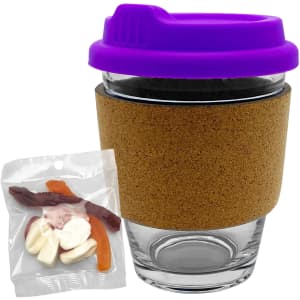 A transparent glass coffee cup with a purple lid and cork band, alongside a pack of mixed lollies.