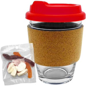 A glass coffee cup with a cork band and a red lid, accompanied by a pack of mixed lollies.