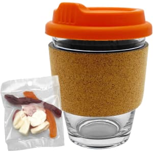 A glass coffee cup with an orange lid and cork band, accompanied by a bag of mixed lollies in various colours.