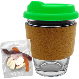 A glass coffee cup with a cork band and a green lid, accompanied by a pack of mixed lollies.