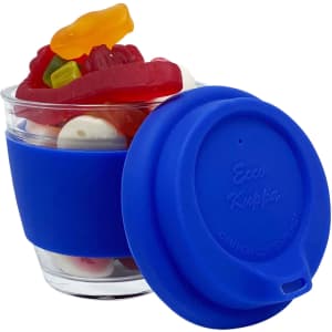A glass coffee cup with a blue silicone sleeve, filled with various colourful jelly lollies.