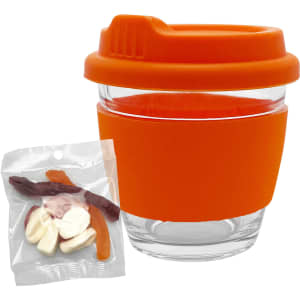 A clear glass coffee cup with an orange silicone lid and sleeve, accompanied by a bag of mixed jelly lollies.