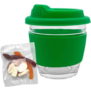 A green glass coffee cup with a silicone lid and sleeve, accompanied by a packet of mixed lollies in various colours.