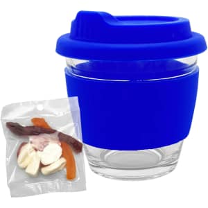 A blue glass coffee cup with a silicone lid and sleeve, alongside a packet of mixed lollies in various colours.