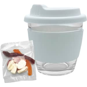 A glass coffee cup with a light blue silicone sleeve, accompanied by a pack of mixed jelly lollies in various colours.