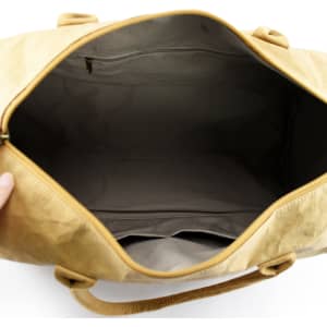 A tan kraft paper duffle bag with a spacious interior and zip closure, featuring inner pockets and a logo.