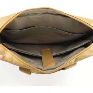 An interior view of a tan kraft paper business satchel with compartments and a zip closure. It features a soft lining.