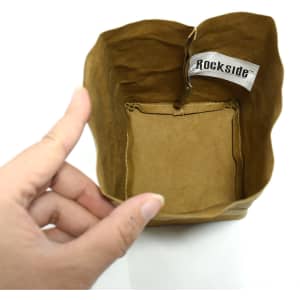 A small brown kraft paper storage bag with a decorative tag inside, being held by a hand.