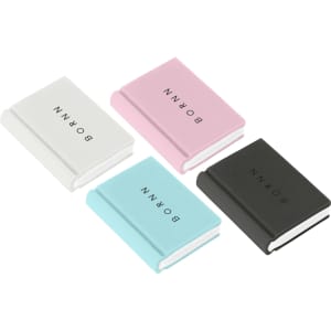 A set of four book-shaped rubber erasers in white, pink, light blue, and black, featuring simple branding.