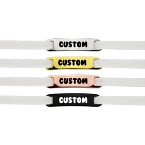 Four shoelace charms in white, yellow, pink, and black, each with a customisable design and featuring a logo.