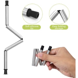 A foldable metal straw in silver with a soft silicone tip, featuring easy folding for storage. There is a hand holding the straw.