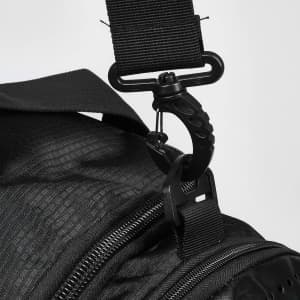 A close-up of a black duffle bag strap with a metal clip attachment. The bag has a textured surface.