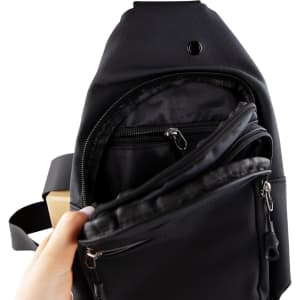 A black sling bag is shown, featuring multiple zippered pockets and a hand holding it open to display the interior.