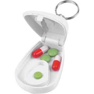 A white pill cutter with a keyring, holding red and green capsules and a green tablet inside.