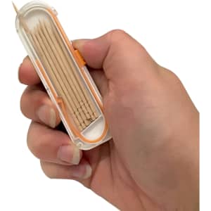 A hand holding a transparent container with a variety of wooden toothpicks inside, featuring an orange accent.