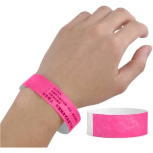 A pink Tyvek wristband worn on a hand, featuring a textured surface and a logo.