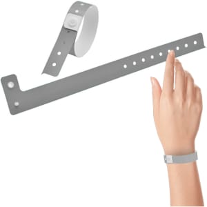 A grey vinyl wristband with a button closure, displayed on a hand and lying flat next to it.