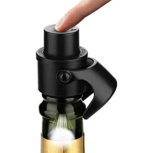A black champagne stopper is being pressed down on a green bottle, featuring a finger on top. The product has a sleek design.