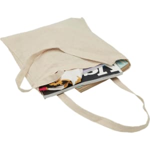 A natural-coloured hemp tote bag filled with magazines. The bag has two handles and a simple design.