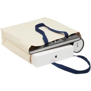 A cream heavy-duty canvas tote with navy handles, filled with various items including books and a box.