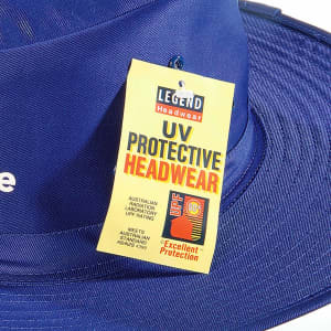 A blue Poly Viscose Slouch Hat with a tag indicating UV protective features and a logo.