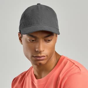 A grey recycled corduroy cap with a curved brim, worn by a person in a coral shirt. The cap features a logo.