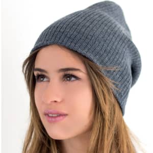 A grey beanie with a ribbed texture, worn by a model with long hair, featuring a logo on the side.