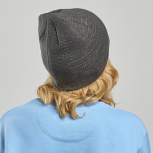 A dark grey beanie viewed from the back, worn by a person with wavy blonde hair, with a blue sweatshirt visible.
