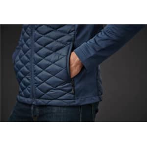 A men's thermal shell jacket in navy blue featuring a quilted design and side pockets. The model's hand is in a pocket.