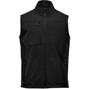 A black softshell vest with a high collar, zippered front, and multiple pockets. Features a logo on the garment.