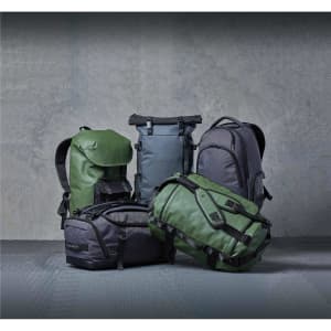 Five backpacks in various shades of green and grey, featuring different styles and designs, with logos visible.