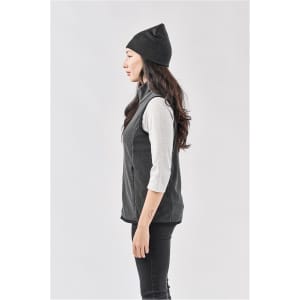 A woman in profile wearing a dark grey beanie and a light grey long-sleeve top, paired with a grey vest.