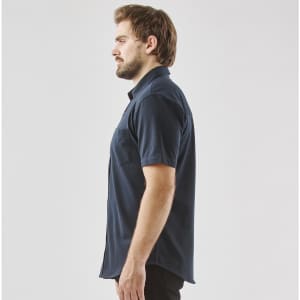 A dark navy short sleeve button-up shirt displayed on a model from the side, featuring a pocket and a logo.