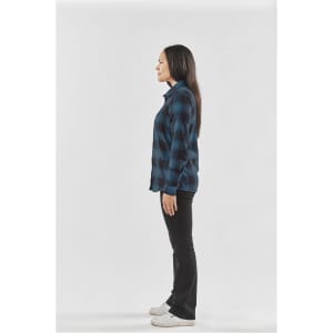 A side view of a woman wearing a blue and black checkered button-up shirt and black pants.