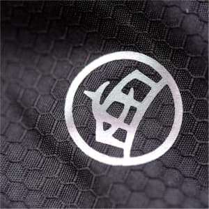 A close-up of a black textured fabric featuring a circular logo. The texture resembles a honeycomb pattern.