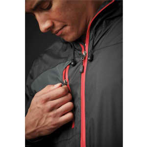 A man in a black rain jacket with red accents, adjusting the zipper near his chest. The jacket features a logo.