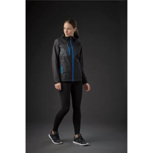 A woman wearing a black rain jacket with blue accents, paired with black leggings and sneakers.