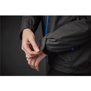 A black rain jacket featuring blue accents, focusing on a hand adjusting the cuff. It includes a logo.
