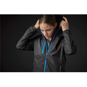A woman adjusts the hood of a black rain jacket with blue accents. The jacket features a zip-up front and pockets.