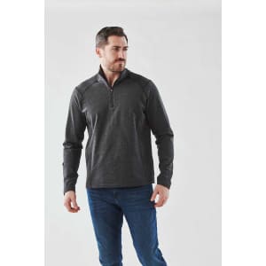 A man wearing a dark grey 1/4 zip pullover, featuring long sleeves and a logo on the chest.