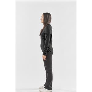 A side view of a woman wearing a black long-sleeve crew neck shirt and black pants, with a logo on the shirt.