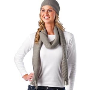 A woman wearing a grey knitted scarf and beanie, with her hair cascading down and a white long-sleeve top.
