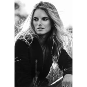 A model poses outdoors wearing a black softshell fleece hybrid jacket, with her hair flowing in the wind.