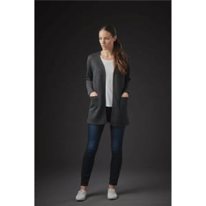 A woman wearing a dark grey Chelsea open cardigan over a white top, paired with dark jeans and casual white shoes.