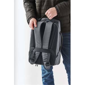 A grey Toluca backpack being held by a person, featuring padded straps and a sleek design.
