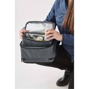 A grey backpack with a silver insulated interior, held open by a person while showcasing its storage space.