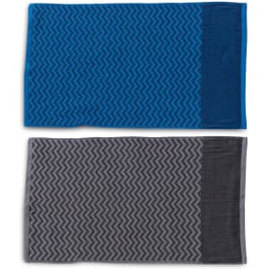 Two gym towels displayed, one in blue with a patterned design and the other in grey with a similar pattern, both featuring a pocket.